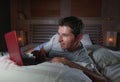 Young attractive and relaxed man networking at home lying comfortable on bed late night happy watching movie on laptop computer or Royalty Free Stock Photo