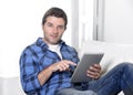 Young attractive 30s man using digital tablet pad lying on couch at home living room networking looking relaxed and happy Royalty Free Stock Photo