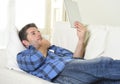 Young attractive 30s man using digital tablet pad lying on couch at home networking looking relaxed Royalty Free Stock Photo