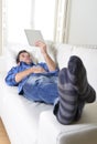 Young attractive 30s man using digital tablet pad lying on couch at home networking looking relaxed Royalty Free Stock Photo