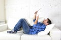 Young attractive 30s man using digital tablet pad lying on couch at home networking looking relaxed Royalty Free Stock Photo