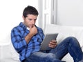 Young attractive 30s man using digital tablet pad lying on couch at home networking looking relaxed Royalty Free Stock Photo
