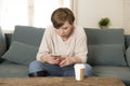 Young attractive 30s red hair woman upset bored and moody using internet app on mobile phone sitting at home sofa couch in annoyed Royalty Free Stock Photo