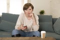 Young attractive 30s red hair woman upset bored and moody using internet app on mobile phone sitting at home sofa couch in annoyed Royalty Free Stock Photo