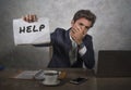 Young attractive sad and depressed business man working at office laptop computer desk holding notepad asking for help feeling des Royalty Free Stock Photo