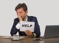 Young attractive sad and depressed business man working at office laptop computer desk holding notepad asking for help feeling des Royalty Free Stock Photo