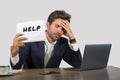 Young attractive sad and depressed business man working at office laptop computer desk holding notepad asking for help feeling des Royalty Free Stock Photo