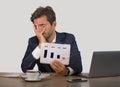 Young attractive sad and depressed businessman working in stress at office computer desk showing sales benefit drop graph feeling