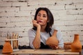 Young and attractive sad female potter working in a studio with a brown clay vase pot in the craft workshop holding the Royalty Free Stock Photo