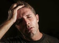 Young attractive and sad man suffering depression and headache with hand on his tempo head in stress looking worried and sick iso Royalty Free Stock Photo