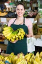 young attractive salesgirl proposing fresh bananas in supermarket Royalty Free Stock Photo