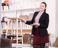 Saleswoman offering bar stools in furniture store