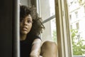 Young attractive sensual black woman sitting near the window looking at the camera