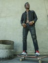 Young attractive and serious black African American man riding skate board at grunge street corner looking cool posing in badass Royalty Free Stock Photo