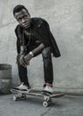 Young attractive and serious black afro American man squatting on skate board at grunge street corner looking cool posing in Royalty Free Stock Photo