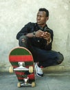 Young attractive and serious black afro American man squatting on skate board at grunge street corner posing in badass bad boy Royalty Free Stock Photo