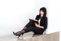 Young Attractive serious brunette woman dressed in a black business suit sitting on a floor in a office, writing in a notebook Royalty Free Stock Photo