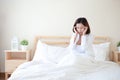 Young attractive and sexy asian woman wearing white shirt got headache on bed in white bedroom with unhappy face Royalty Free Stock Photo