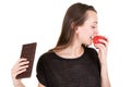 Young attractive slim woman holding apple and chocolate bar in her hands in healthy fruit versus sweet junk food temptation in Royalty Free Stock Photo