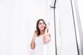 Young attractive smiling caucasian girl standing on background of window, talking per mobile phone. Royalty Free Stock Photo