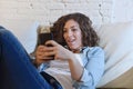 Young attractive spanish woman using mobile phone app or texting on home couch Royalty Free Stock Photo