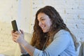 Young attractive spanish woman using mobile phone app or texting on home couch Royalty Free Stock Photo