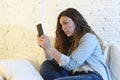 Young attractive spanish woman using mobile phone app or texting on home couch Royalty Free Stock Photo