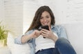 Young attractive spanish woman using mobile phone app or texting on home couch Royalty Free Stock Photo