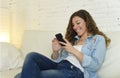 Young attractive spanish woman using mobile phone app or texting on home couch Royalty Free Stock Photo