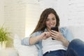 Young attractive spanish woman using mobile phone app or texting on home couch Royalty Free Stock Photo