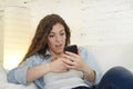 Young attractive spanish woman using mobile phone app or texting on home couch Royalty Free Stock Photo