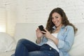 Young attractive spanish woman using mobile phone app or texting on home couch Royalty Free Stock Photo