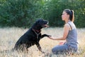 Young attractive sport girl with black Labrador in park. Healthy lifestyle. Trains dog to give a paw