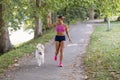 Young attractive sport girl running with dog in park Royalty Free Stock Photo