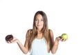 Young attractive sport woman holding apple and chocolate donut in her hands in healthy fruit versus sweet junk food temptation Royalty Free Stock Photo