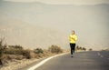 Young attractive sport woman running on asphalt road with desert mountain landscape background Royalty Free Stock Photo