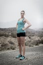 Young attractive sport woman in running singlet and shorts posing defiant and cool in asphalt road in front of mountain Royalty Free Stock Photo