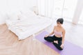 Young attractive sporty Asian woman practicing yoga on a yoga mat, doing Ardha Padmasana exercise, meditating in Half Lotus pose, Royalty Free Stock Photo