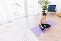 Young attractive sporty Asian woman practicing yoga on a yoga mat, doing Ardha Padmasana exercise, meditating in Half Lotus pose. Royalty Free Stock Photo