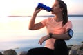 Young attractive sporty fitness woman drinking water exercise in beach outdoor portrait, at sunset or sunrise. Royalty Free Stock Photo