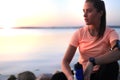 Young attractive sporty fitness woman drinking water exercise in beach outdoor portrait, at sunset or sunrise. Royalty Free Stock Photo