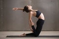 Young attractive sporty woman in Ustrasana pose, grey studio bac