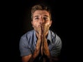 Young attractive stressed man with hands palms together praying and wishing success to come looking concentrated hoping for good l Royalty Free Stock Photo