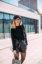 Young attractive stylish smiling woman having fun in city , positive, emotional, long hair, wearing leather shorts and black Royalty Free Stock Photo