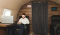 Young attractive and successful businessman is resting and listening to music works while sitting in the chair of his Royalty Free Stock Photo