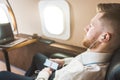 Young attractive and successful businessman is resting and listening to music works while sitting in the chair of his Royalty Free Stock Photo