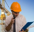 Young attractive and successful engineer man or architect working on building at construction site wearing hardhat holding Royalty Free Stock Photo