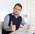 Young attractive successful manager with thumb up at office.