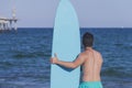 Young attractive surfer holding his surfboard at the beach Royalty Free Stock Photo