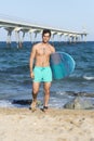 Young attractive surfer holding his surfboard at the beach Royalty Free Stock Photo